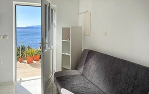 A room with a grey sofa, a white door, and a view of the sea. - Gorgeous apartment in Podgora with WiFi (Podgora)