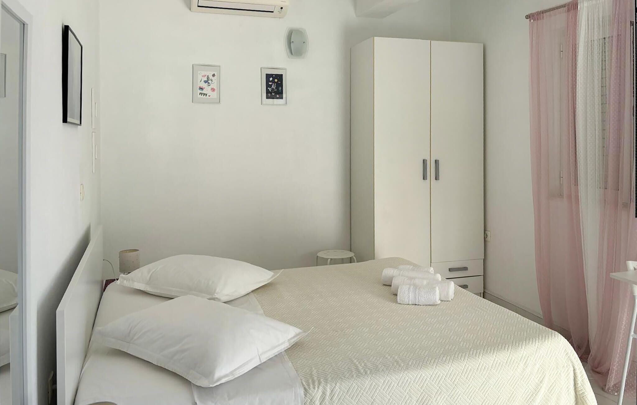 Ein Schlafzimmer mit einem Bett, Kissen, einem Kleiderschrank und einem kleinen Tisch mit Handtüchern.
