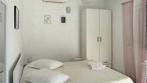 A bedroom with a bed, pillows, a wardrobe, and a small table with towels. - Gorgeous apartment in Podgora with WiFi (Podgora)