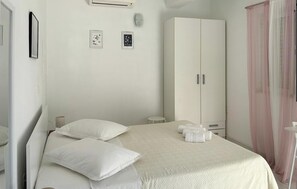Ein Schlafzimmer mit einem Bett, Kissen, einem Kleiderschrank und einem kleinen Tisch mit Handtüchern.