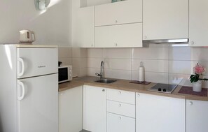 A compact kitchen with white cabinetry, a built-in microwave, a sink, and a kettle on the countertop. - Gorgeous apartment in Podgora with WiFi (Podgora)