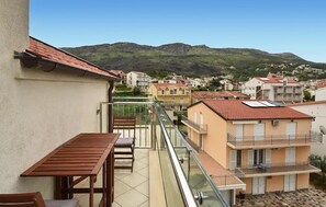 Ein Balkon mit Tisch und Stühlen, mit Blick auf eine Wohngegend mit Häusern und einem Berg im Hintergrund.
