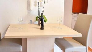 A dining table with two chairs, a vase with flowers, and two wine glasses. - Stunning apartment in Podstrana with WiFi (Podstrana)