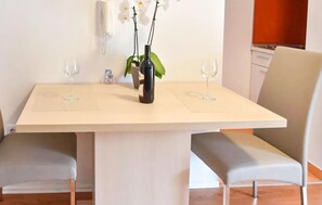 A dining table with two chairs, a vase with flowers, and two wine glasses. - Stunning apartment in Podstrana with WiFi (Podstrana)
