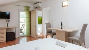 Una habitación de hotel con una cama, un escritorio, dos sillas, un televisor y una botella de vino.