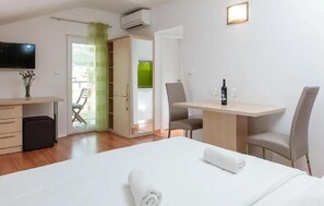 A hotel room with a bed, a desk, two chairs, a TV, and a bottle of wine. - Cozy apartment in Podstrana with WiFi (Podstrana)