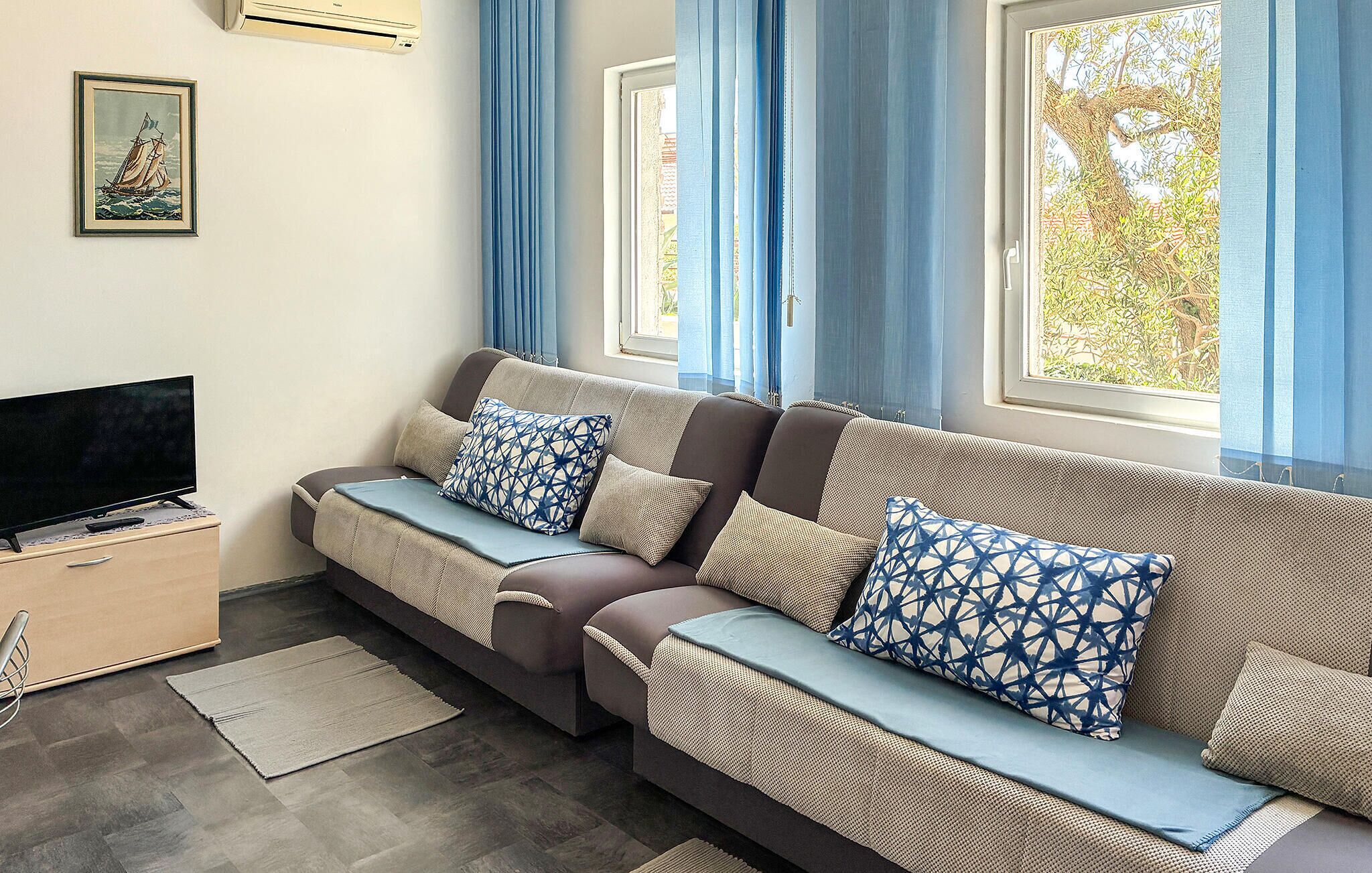 A modern living room with a sofa, a flat-screen TV, and a framed picture on the wall.