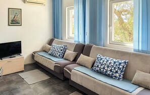 A modern living room with a sofa, a flat-screen TV, and a framed picture on the wall. - Lovely apartment in Pisak with WiFi (Pisak)