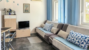 A modern living room with a sofa, a flat-screen TV, a desk, and a chair. - Lovely apartment in Pisak with WiFi (Pisak)