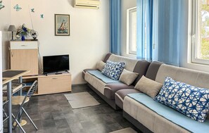 A modern living room with a sofa, a flat-screen TV, a desk, and a chair. - Lovely apartment in Pisak with WiFi (Pisak)