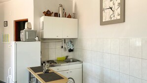 A compact kitchen with a sink, a microwave, and a small table. - Lovely apartment in Pisak with WiFi (Pisak)