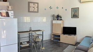 A compact living space with a kitchenette, a dining area, a TV, and a sofa. - Lovely apartment in Pisak with WiFi (Pisak)