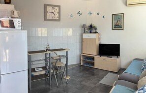 A compact living space with a kitchenette, a dining area, a TV, and a sofa. - Lovely apartment in Pisak with WiFi (Pisak)