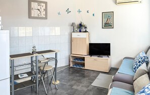 A compact living space with a kitchenette, a TV, a sofa, and a small dining area. - Lovely apartment in Pisak with WiFi (Pisak)