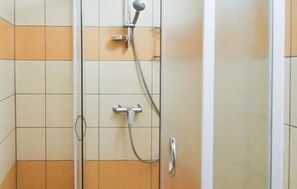 Een douchegedeelte met een handdouche en een kraan op de muur.