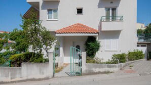 A two-story residential building with a tiled roof, a balcony, and a gated entrance. - Beautiful apartment in Makarska with WiFi (Makarska)