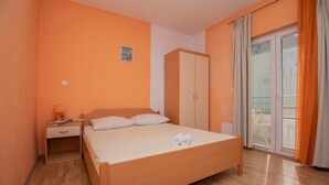 A bedroom with a bed, a wardrobe, a nightstand, and a window with curtains. - Beautiful apartment in Makarska with WiFi (Makarska)