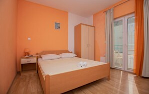 Ein Schlafzimmer mit einem Bett, einem Kleiderschrank, einem Nachttisch und einem Fenster mit Vorhängen.