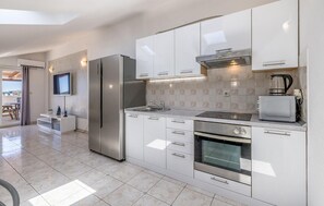 A modern kitchen with white cabinetry, stainless steel appliances, a built-in oven, and a television mounted above the counter. - Cozy home in Trogir with private swimming pool, can be inside or outside (Trogir)