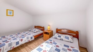 A small, simple room with two single beds, a nightstand with a lamp, and a framed picture on the wall. - Cozy home in Trogir with private swimming pool, can be inside or outside (Trogir)