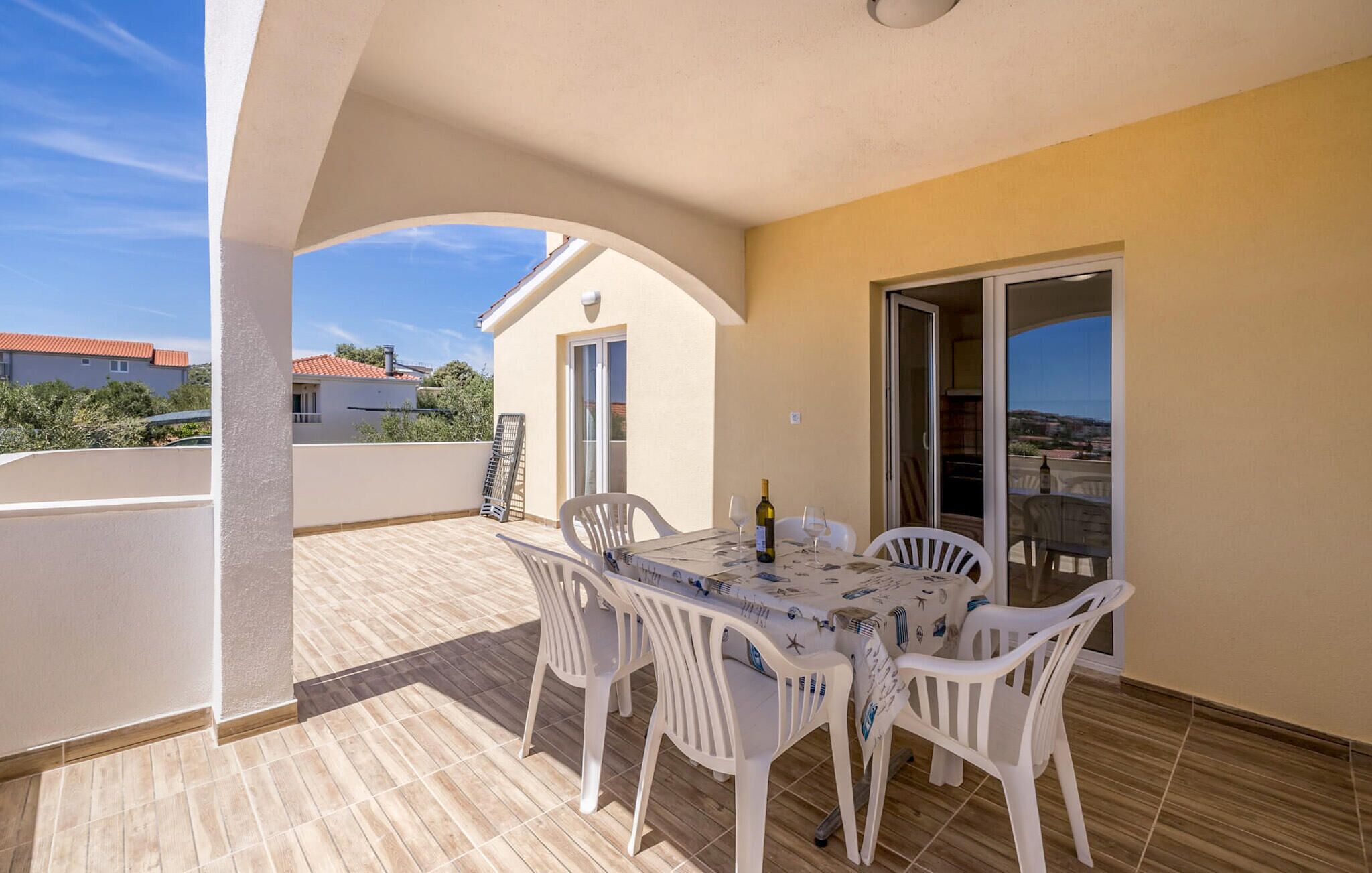 A balcony with a table and chairs, a bottle of wine, and a view of the surrounding area.