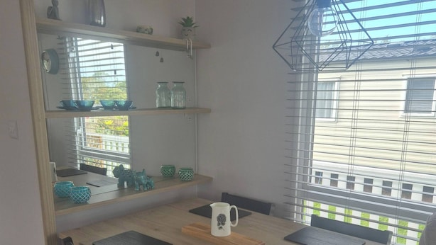Un comedor con una mesa de madera, cuatro sillas y una ventana con persianas.