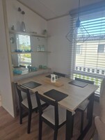 Un comedor con una mesa de madera, cuatro sillas y una ventana con persianas.