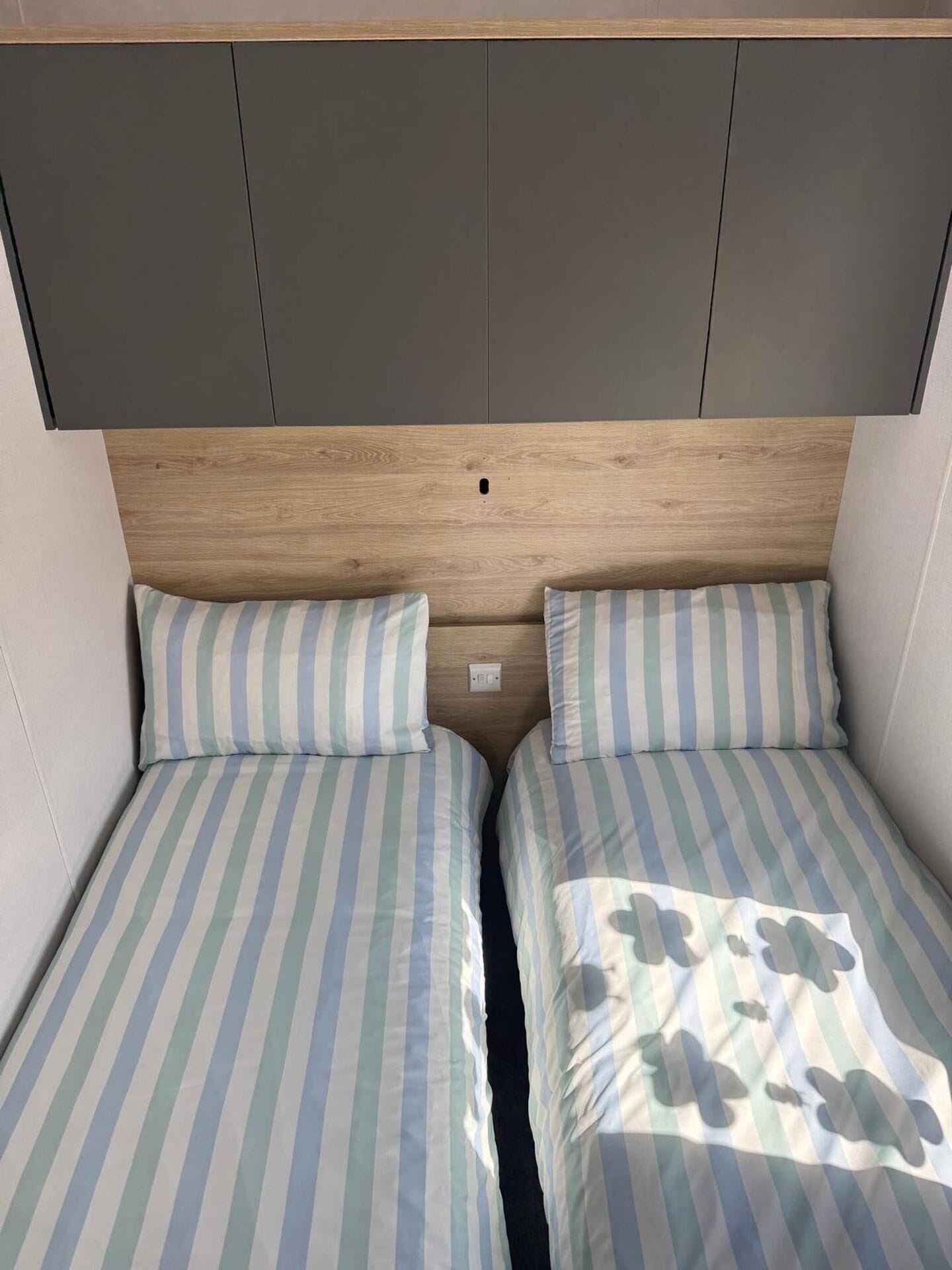 A double bed with striped bedding and a headboard with a central cut-out.