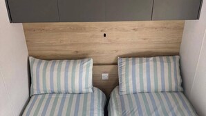 Una cama doble con ropa de cama a rayas y un cabecero con un hueco central.