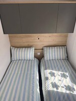Una cama doble con ropa de cama a rayas y un cabecero con un hueco central.