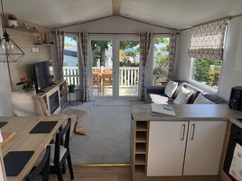 Un espacio habitable compacto con kitchenette, comedor y zona de estar con vistas al exterior.