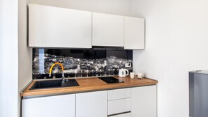 A compact kitchen with a black backsplash, white cabinets, a wooden countertop, a sink, a coffee maker, and a kettle. - Stunning apartment in Sibenik with house sea view (Sibenik)