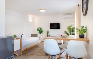 Ein modernes, helles Schlafzimmer mit Bett, Nachttisch und Fernseher.