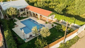 Propiedad residencial con piscina, terraza techada y patio cercado.