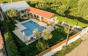 Ein Wohnhaus mit Pool, überdachter Terrasse und eingezäunter Garten.