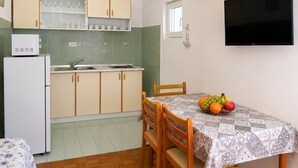 Una cuina compacta amb nevera, rentamiques i un plat de fruita sobre la taula.