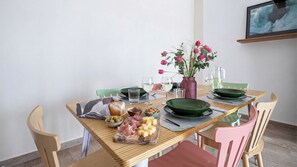 Una mesa de comedor con diversos alimentos, como queso, carnes y aceitunas, dispuesta para una comida.