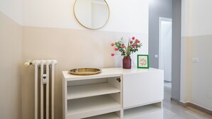 A white vanity with a gold tray, a mirror, a vase with flowers, and a framed picture. - Italianway Comfort - Via Torre 24 (Milan)