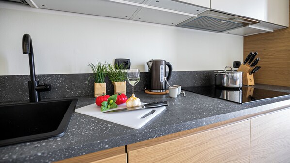 A modern kitchen with a black sink, a white cutting board with vegetables, a kettle, and a knife block. - Italianway Comfort - Via Torre 24 (Milan)