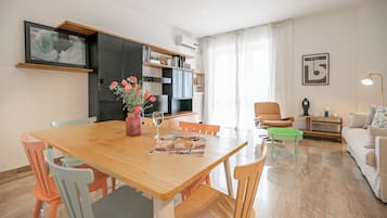 Un'area pranzo con un tavolo di legno, sedie, un vaso con fiori e un quadro appeso al muro.