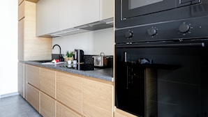 A modern kitchen with a black oven, stainless steel appliances, and wooden cabinetry. - Italianway Comfort - Via Torre 24 (Milan)