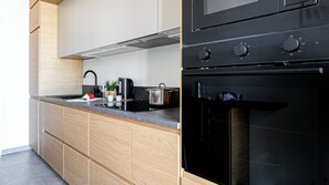 Una cocina moderna con horno negro, electrodomésticos de acero inoxidable y muebles de madera.