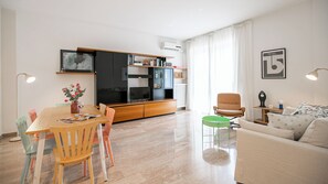 A modern living room with a dining area, a sofa, a television, and a bookshelf. - Italianway Comfort - Via Torre 24 (Milan)