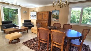 Un coin repas comprenant une table ronde, six chaises, un buffet en bois et un lustre.