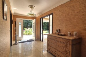 Ein Flur mit Holzwand, einer Glastür, die nach draußen führt, und einer Holzkommode mit Dekorationselementen.