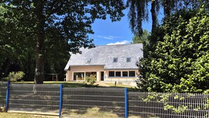 A house with a sloped roof, a fenced yard, and trees.