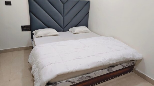 A bed with a headboard, two pillows, and a white bedspread. - Hotel CS Inn & Restaurant (Agra)