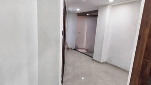 A hallway with a tiled floor, white walls, and a wooden door frame. - Hotel CS Inn & Restaurant (Agra)