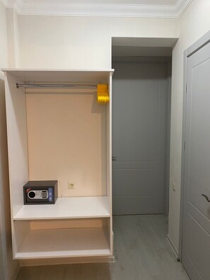 Quarto de hotel com um guarda-roupa, uma pequena prateleira e uma porta que dá para outro aposento.