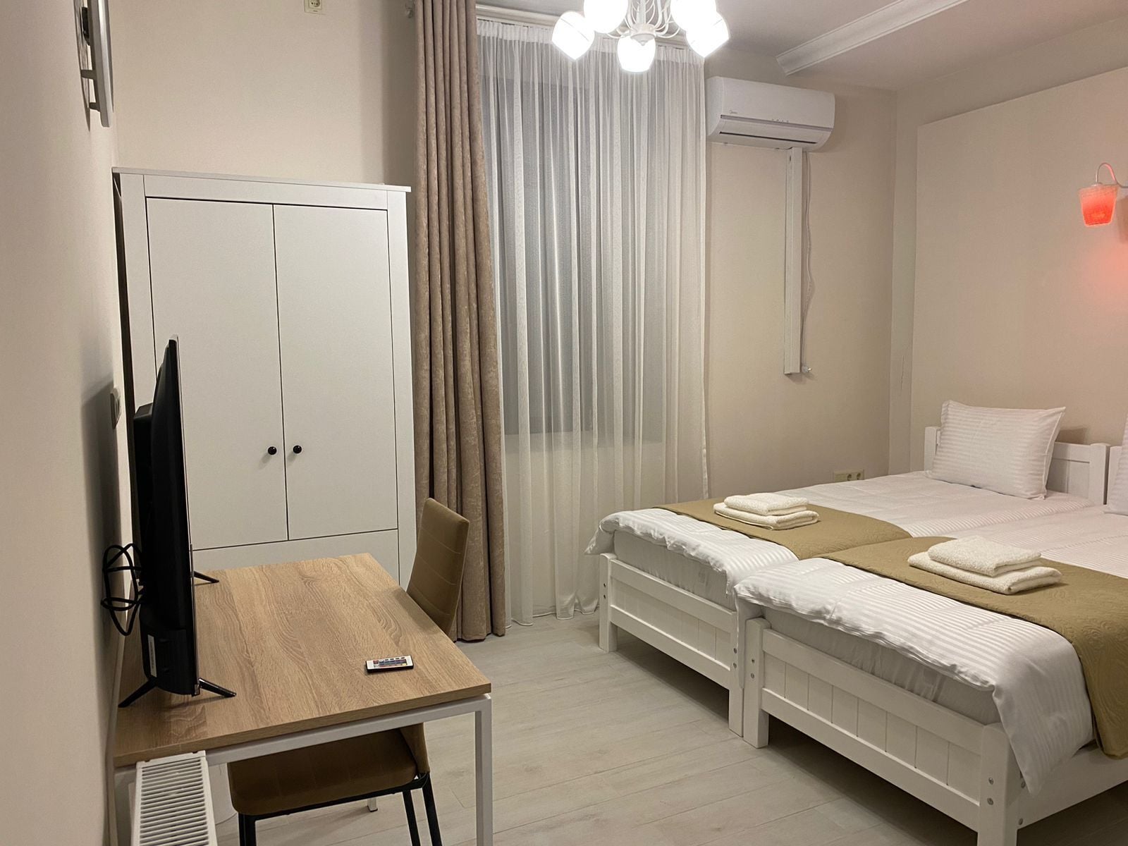 Habitación de hotel con cama, escritorio, armario y aire acondicionado.